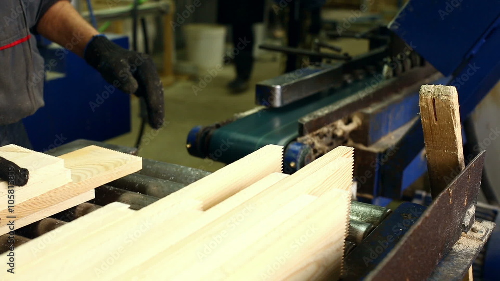 Sawmill. Worker loads wooden slats on conveyor Sawmill. Worker loads wooden slats on conveyor