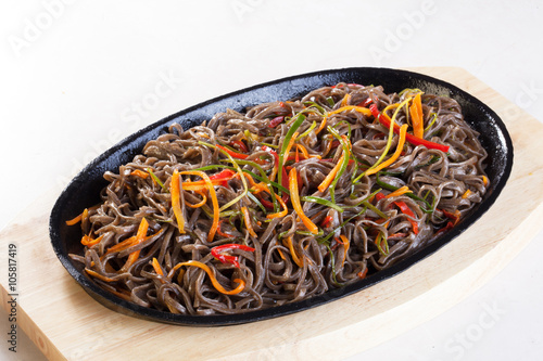 wok buckwheat noodles with vegetables carrots pepper leek cast-iron frying pan on a wooden