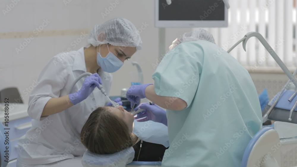 Dentist and dental assistant working on patient's teeth in a real dental surgery Dentist and dental assistant working on patient's teeth in a real dental surgery