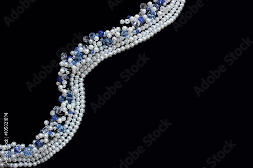 White pearls and blue crystals on the black background