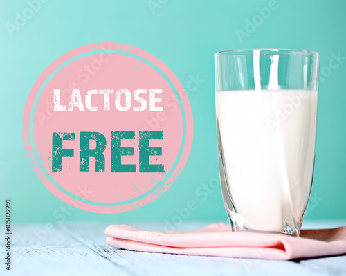 Pitcher of milk on wooden table and lactose free sign on blue background