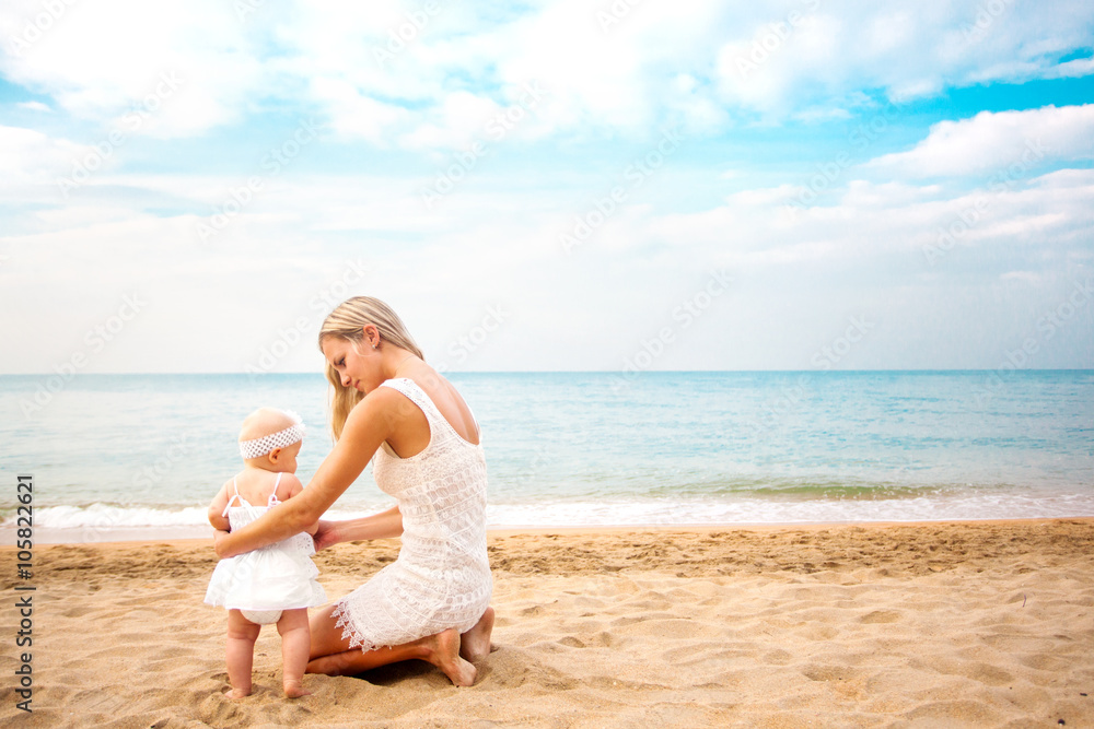 Mother playing with baby on beach. Rear view. Mother playing with baby on beach. Rear view.