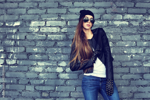 fashion model with long hair wearing sunglasses posing outdoor.