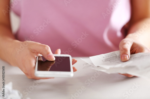 Woman with bills and smart phone at the table. Calculation of costs © Africa Studio