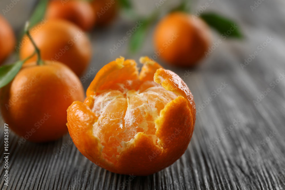 Peeled fresh tangerines with leaves and ripe mandarins on wooden table, closeup Peeled fresh tangerines with leaves and ripe mandarins on wooden table, closeup