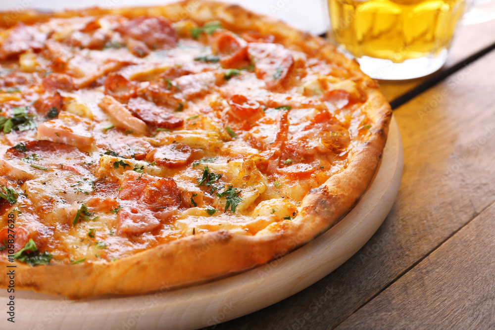 Tasty pizza and glass of beer are on wooden table, close up