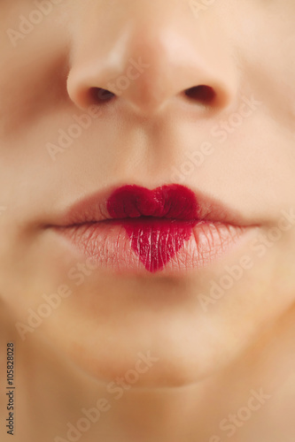 Sexy lips with cherry-coloured heart shape paint  closeup