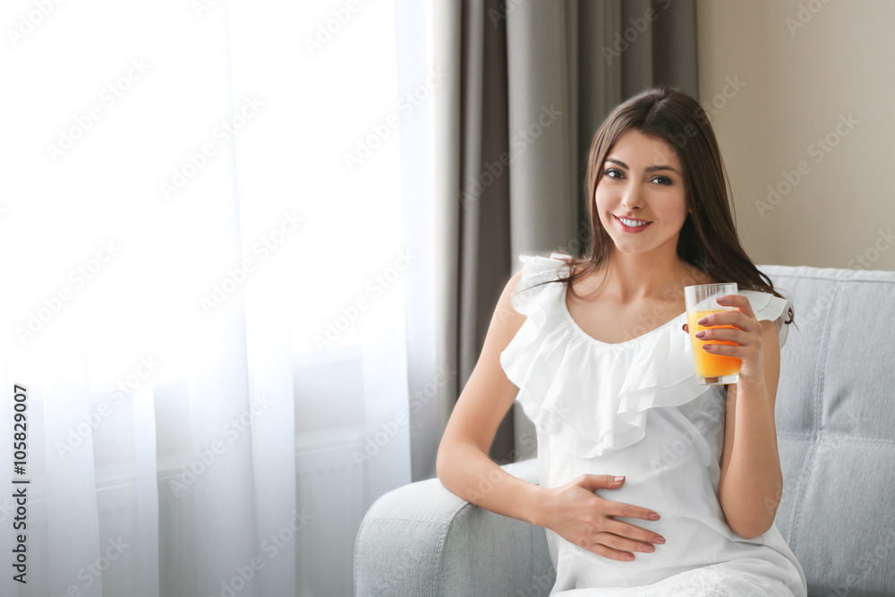 Pregnant woman drinking orange juice in the room Pregnant woman drinking orange juice in the room