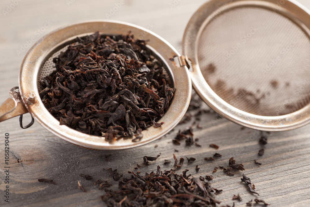 Black tea in metal strainer on a wooden table Black tea in metal strainer on a wooden table