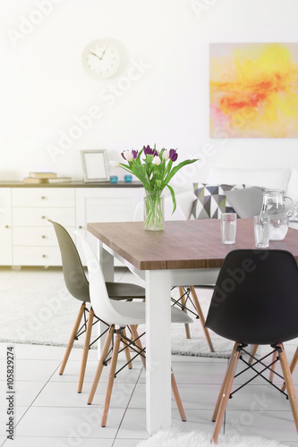 Modern living room. Furniture set with table and chairs. Bouquet of beautiful purple tulips on the table