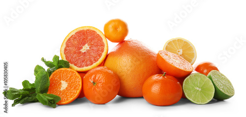 A heap of mixed citrus fruit sliced and unpeeled with mint sprigs isolated on a white background  close up