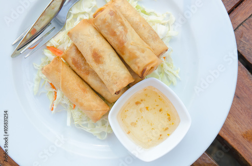 Prawns Spring Rolls with salad and sweet plum dipping sauce of Thai style on wood table.