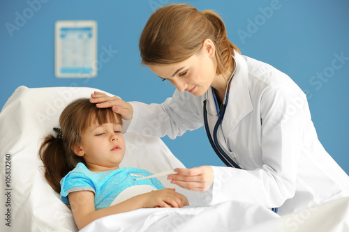 Doctor checking little girl s temperature with a thermometer