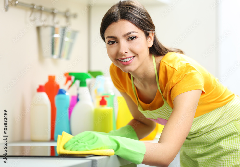 Beautiful woman in protective gloves cleaning electric range with rag Beautiful woman in protective gloves cleaning electric range with rag