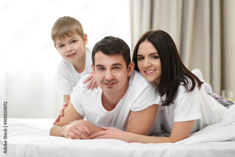 Portrait of happy family with mother, father and son lying in bed Portrait of happy family with mother, father and son lying in bed