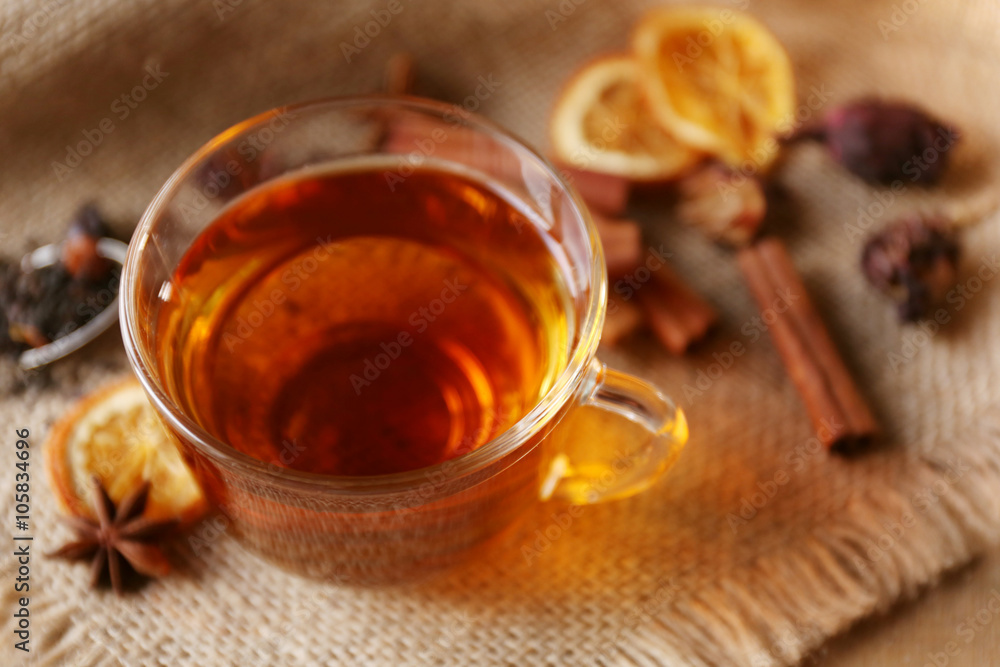 Glass cup of tea with spices on sackcloth closeup Glass cup of tea with spices on sackcloth closeup