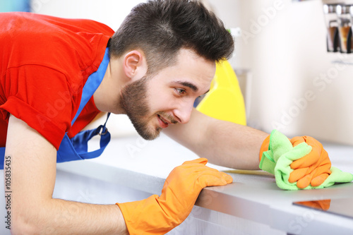 Man cleaning stove in the k...