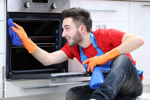 Man cleaning oven in the ki...