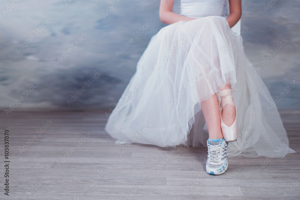 Fototapeta premium Legs of a ballerina, one foot shod in sneakers other in pointe shoes, lifestyle, hobbies, dancing, choice