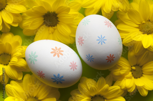 Two white Easter eggs and yellow flowers