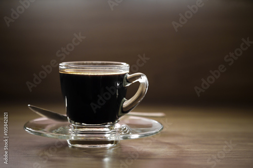 Black coffee cup and spoon on wood