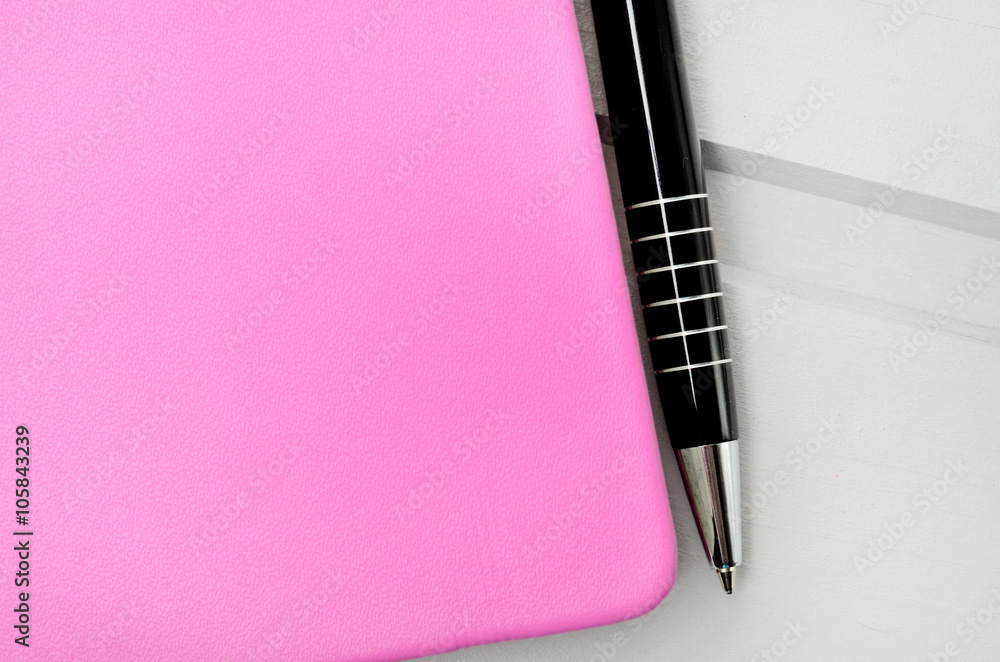 Pink closed notebook with pen Pink closed notebook with pen