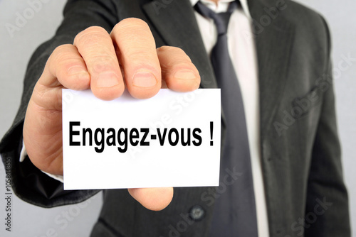Homme tenant une carte où il a a écrit engagez-vous