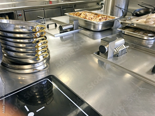 Großküche mit induktionsplatte, gestapelte Pfannen, Fisch und Gemüse auf Gastronorm Bleche 