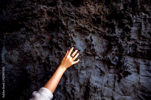 Close-up view on volcanic black rock with female hand in Ajiy caves on Fuerteventura island