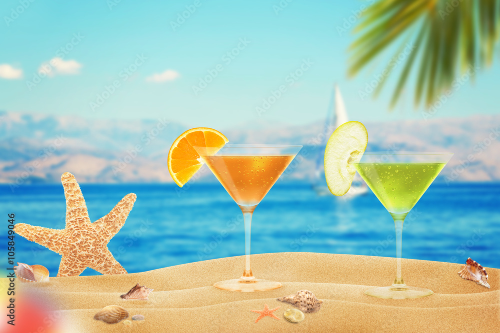 Cocktails on beach. Starfish and shells on sand. Beach and sea with palm in background.