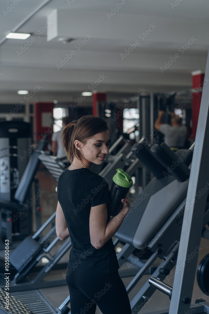 Beautiful girl holding a shaker in the gym Beautiful girl holding a shaker in the gym