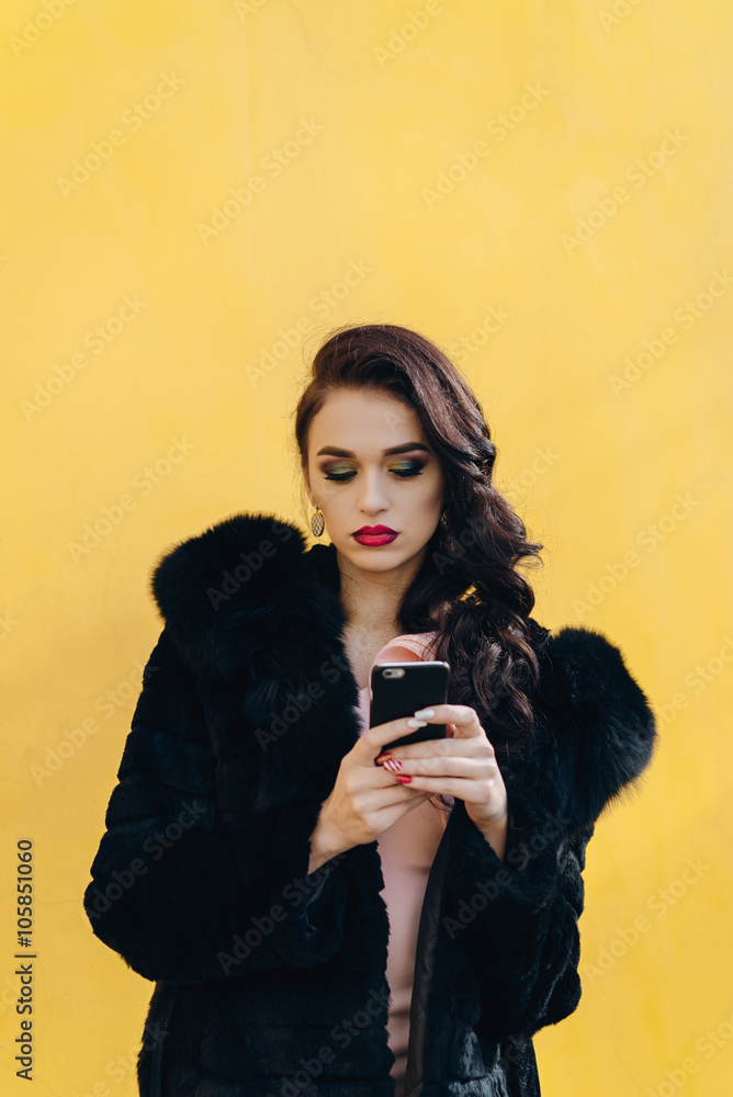 Beautiful girl with the phone on a yellow background