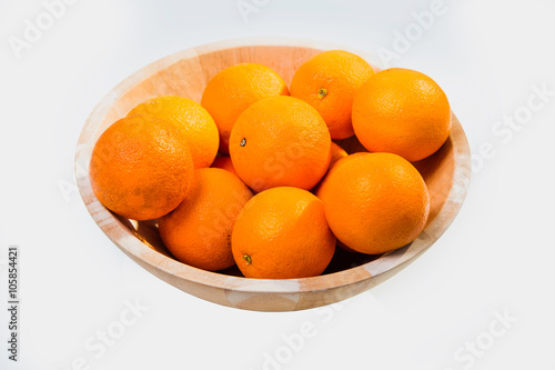 Oranges in large wooden bowl on white background isolated