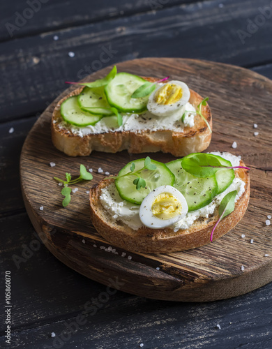 Healthy delicious breakfast or snack - open sandwich with goat's cheese and cucumber and boiled quail eggs
