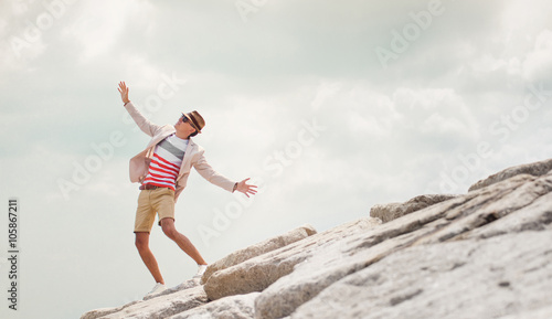 Young man dancing on rock, feel freedom, blue sky background.