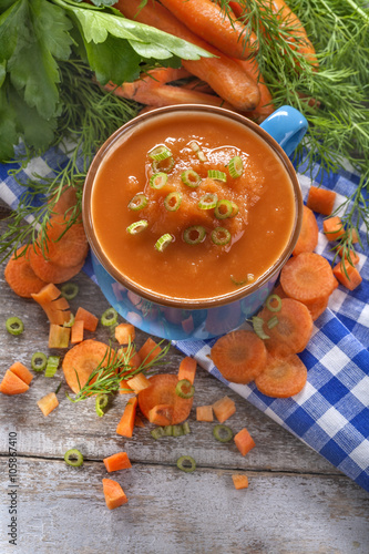 cream soup of carrots in a blue bowl on a rustic wooden table