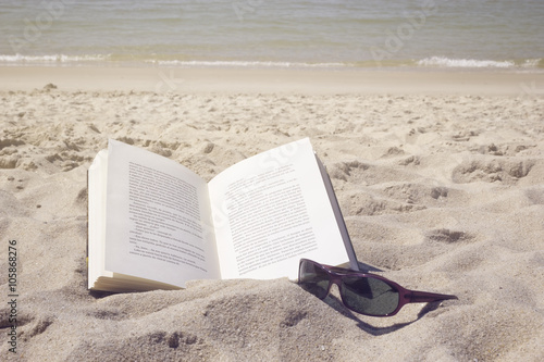 Book and eyeglasses on beach