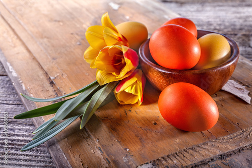 Easter eggs with blossoming tulips on an old rustic table
