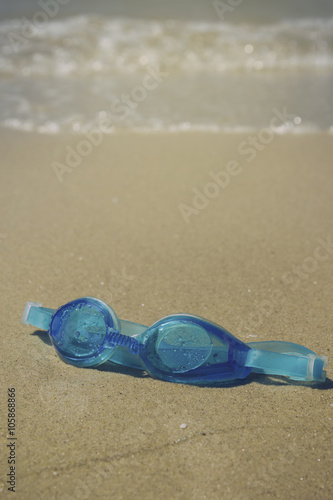 Blue goggles on the beach sand
