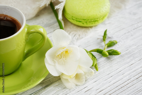 Cup of black coffee, white freesia flowers and sweet pastel fren