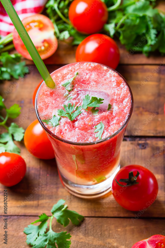 Gass of tomato smoothie, fresh tomatoes and cilantro on a dark wooden background . Vegetarian or healthy eating concept Gass of tomato smoothie, fresh tomatoes and cilantro on a dark wooden background . Vegetarian or healthy eating concept