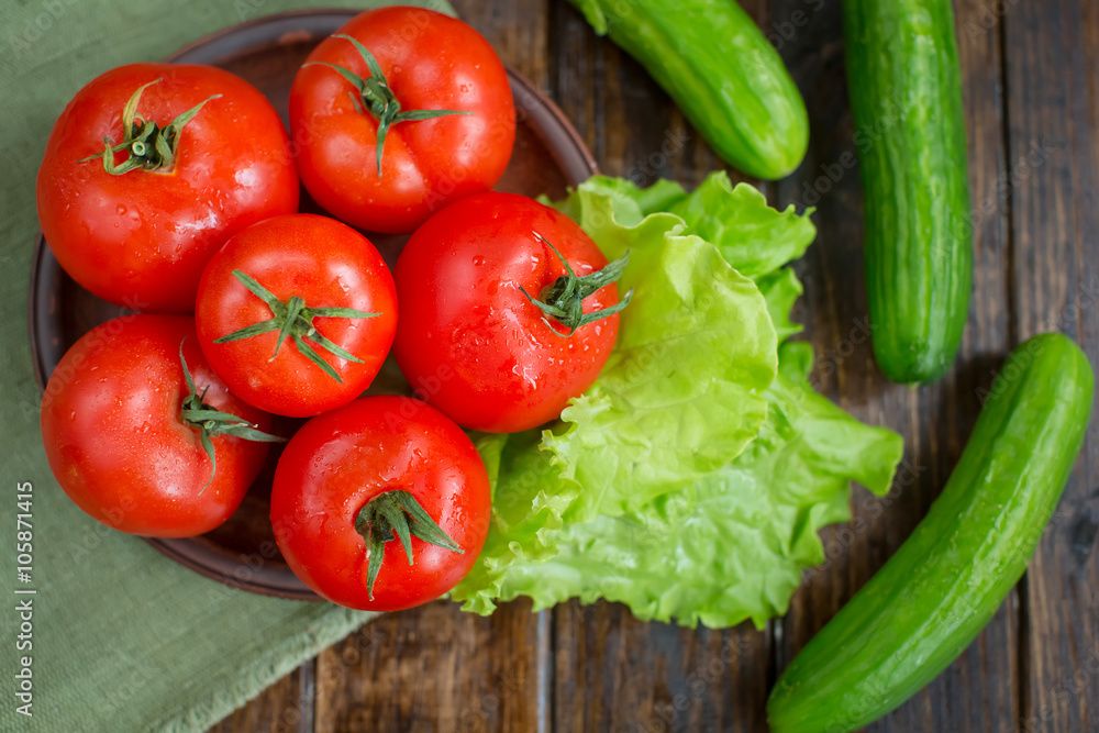 spring vegetables. tomatoes, cucumbers and lettuce on a wooden b spring vegetables. tomatoes, cucumbers and lettuce on a wooden b
