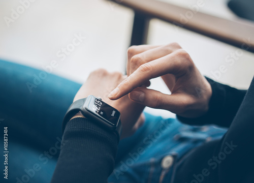 Closeup photo of female hand touching screen generic design smart watch. Film effects, blurred background. Horizontal photo