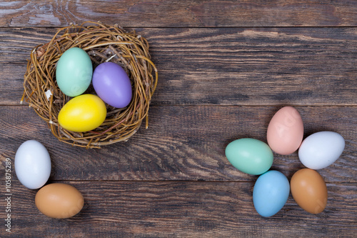 Easter colorful eggs in bird nest on wooden background