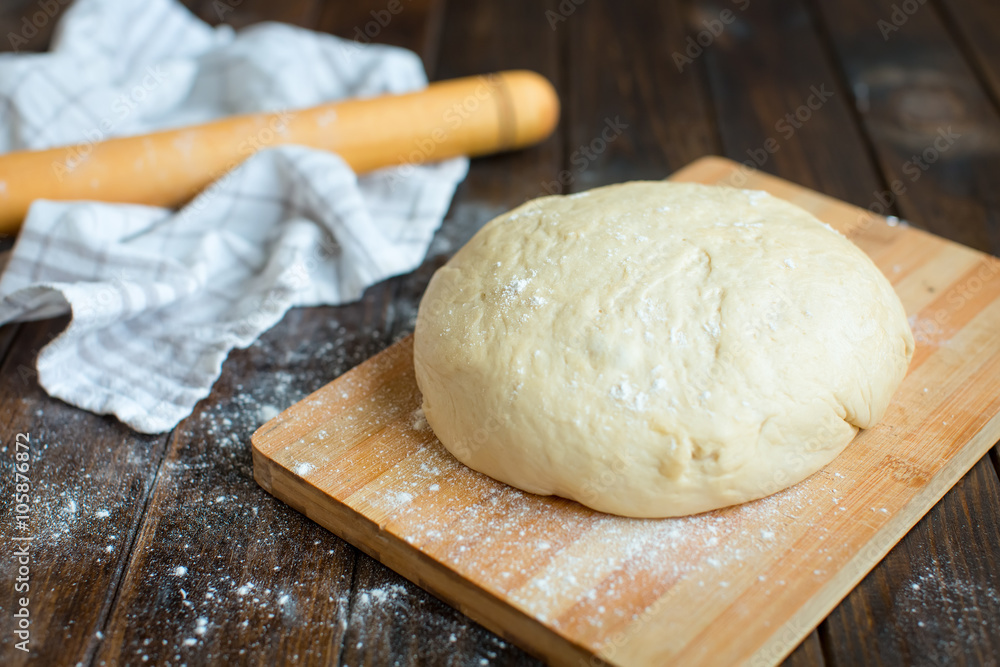 Ball of dough on a rustic wooden background with dusting of flour