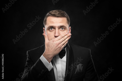Scared man hand covering mouth.