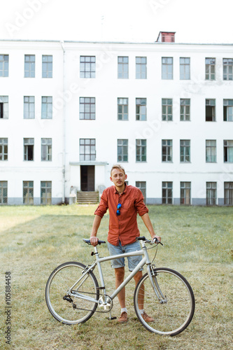 Serious man posing near the bicycle