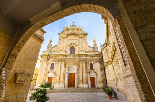 View of Cathedral Maria Santissima della Madia through dark damaged alleyway in old town Monopoli, Italy