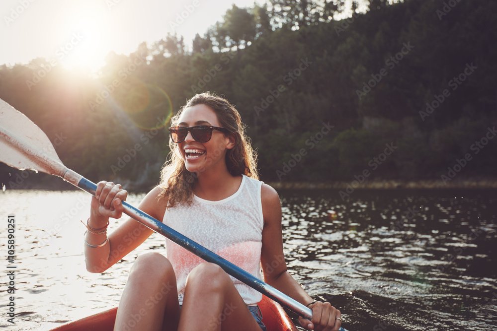 Smiling young woman kayaking on a lake - obrazy, fototapety, plakaty 