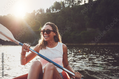Smiling young woman kayaking on a lake